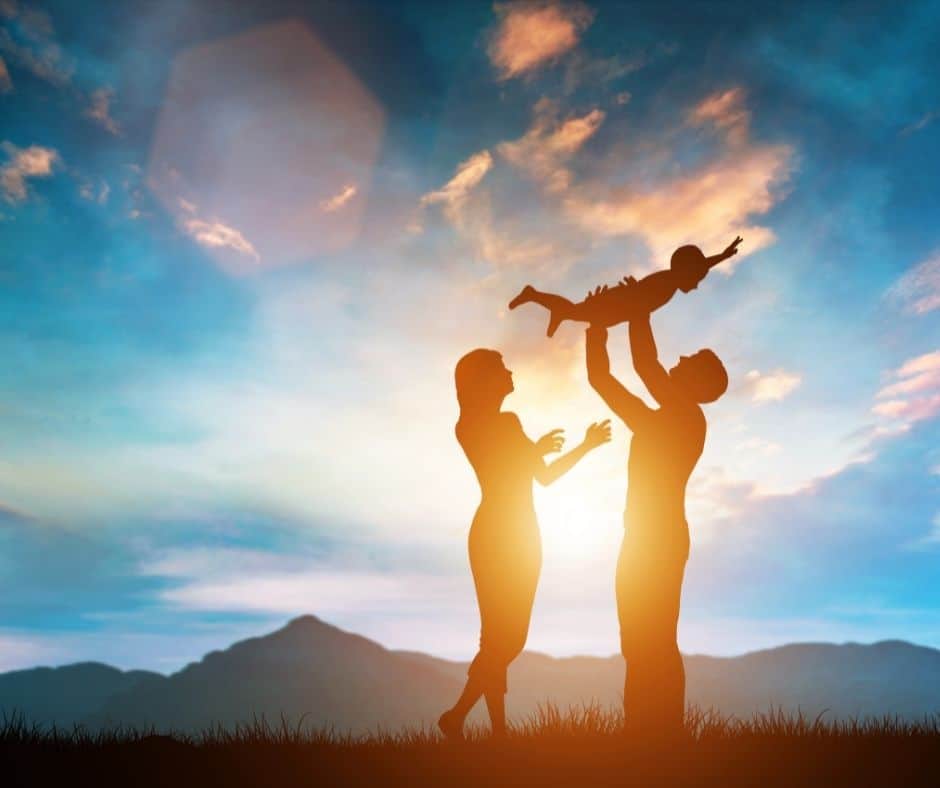 A silhouette of a family holding a child at sunset.