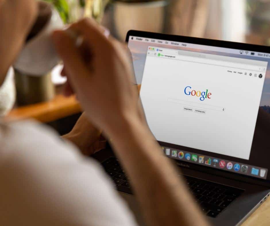 A man is looking at a laptop with the google logo on it.