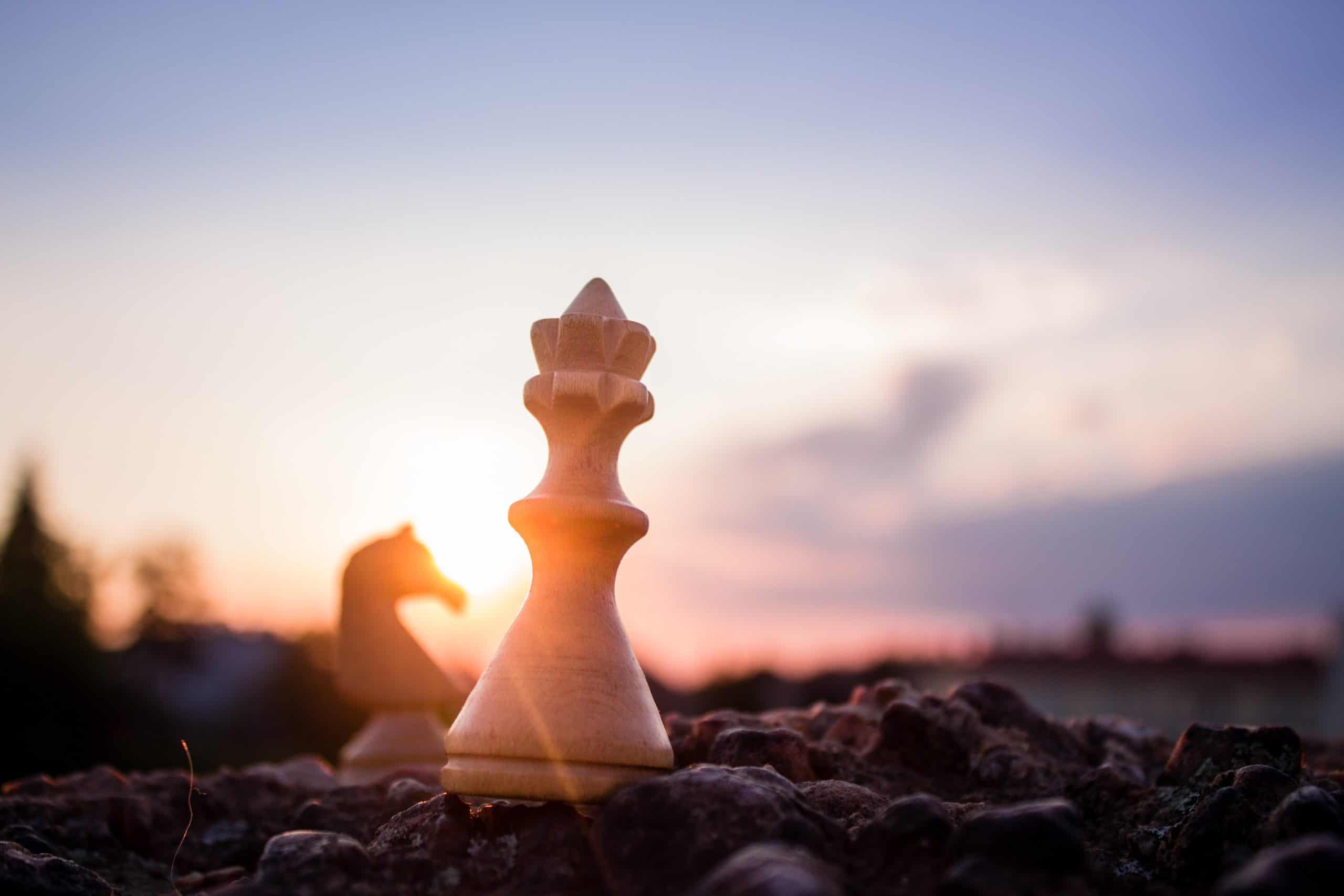 A chess piece sits on top of a rock at sunset.