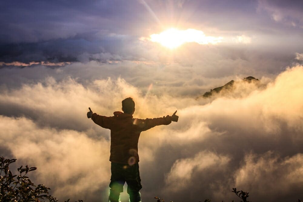 A man standing on top of a mountain with his arms outstretched.