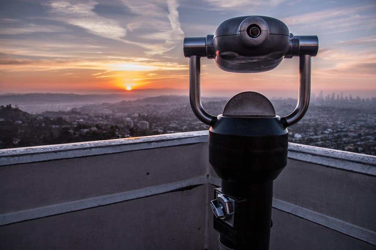 A binocular sits on top of a rooftop overlooking a city.